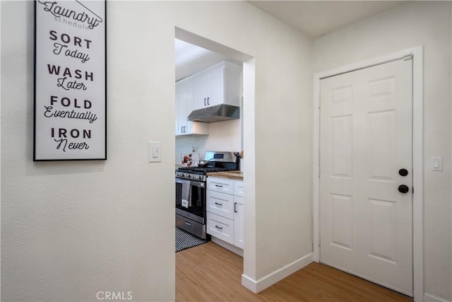 kitchen with white cabinets, light hardwood / wood-style floors, and stainless steel range with gas stovetop