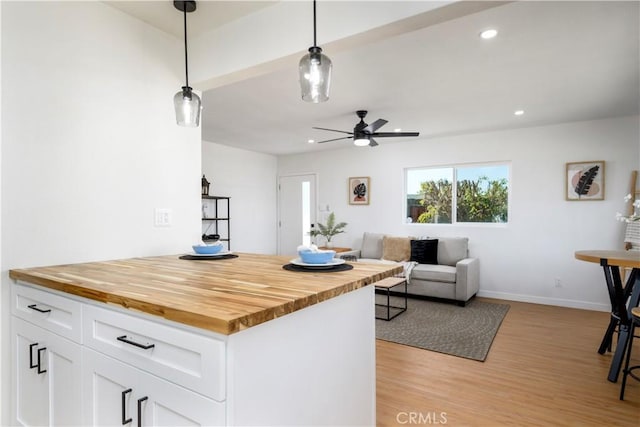 kitchen featuring butcher block counters, ceiling fan, light hardwood / wood-style floors, decorative light fixtures, and white cabinets