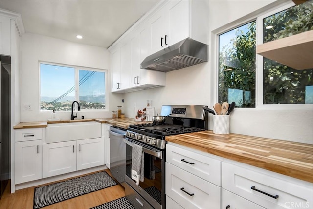 kitchen featuring butcher block countertops, white cabinetry, light hardwood / wood-style flooring, and stainless steel appliances