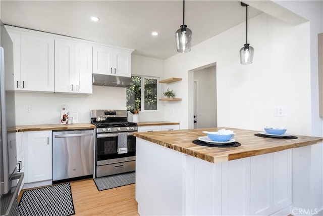 kitchen with butcher block countertops, white cabinets, pendant lighting, and appliances with stainless steel finishes