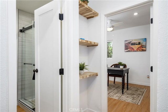 bathroom with hardwood / wood-style flooring, ceiling fan, and a shower with door