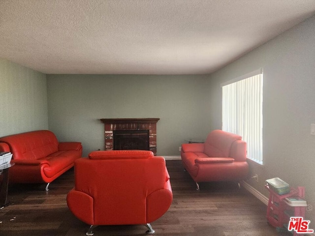 living room with dark hardwood / wood-style floors, a textured ceiling, and a brick fireplace