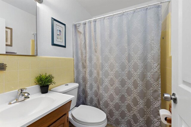 bathroom with vanity, toilet, tile walls, and curtained shower