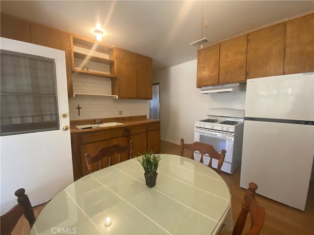 kitchen featuring sink, decorative backsplash, wood-type flooring, and white appliances