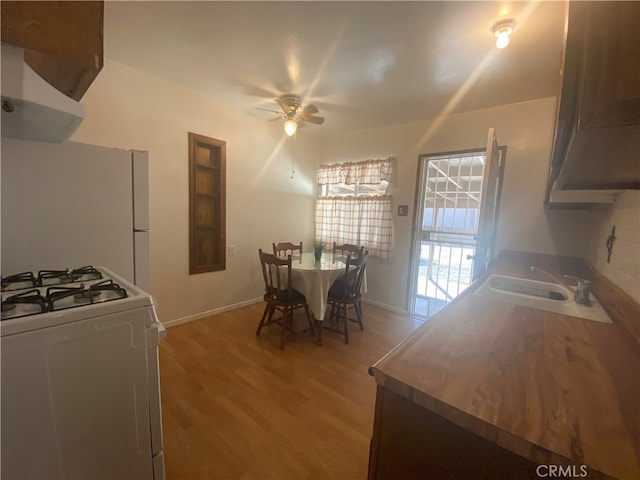 kitchen with sink, white gas range oven, light hardwood / wood-style floors, ceiling fan, and exhaust hood