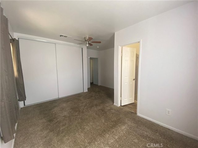 unfurnished bedroom with dark colored carpet, a closet, and ceiling fan