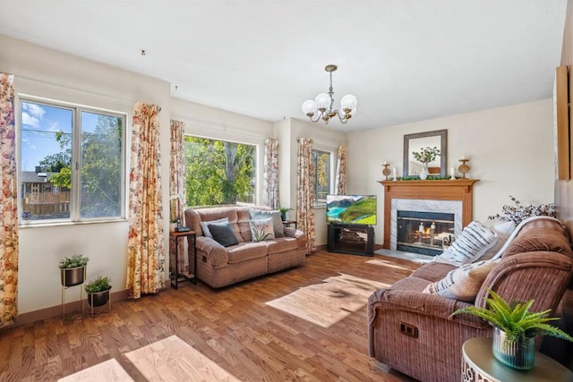 living room featuring light hardwood / wood-style floors, a premium fireplace, and a chandelier