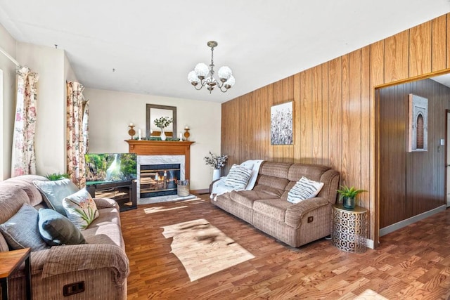 living room featuring hardwood / wood-style flooring, a notable chandelier, and wooden walls