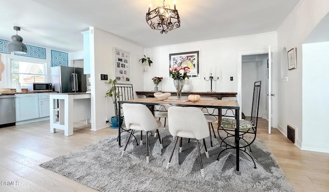 dining space featuring visible vents, baseboards, a notable chandelier, and light wood-type flooring