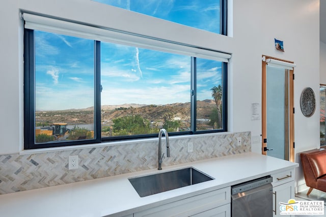 kitchen with backsplash, a mountain view, sink, dishwasher, and white cabinetry