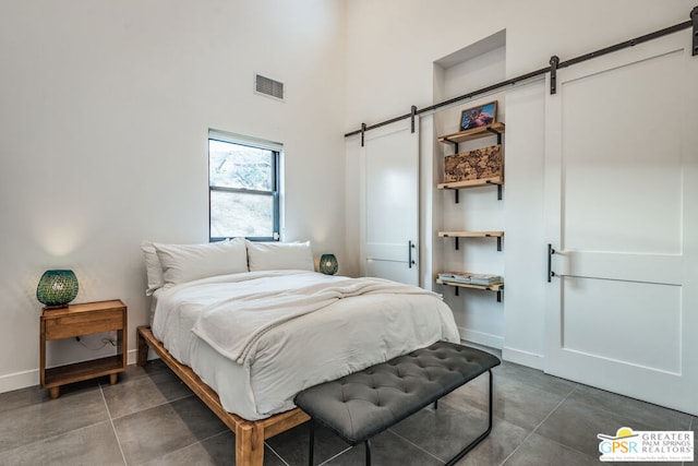 bedroom with a barn door and dark tile patterned flooring