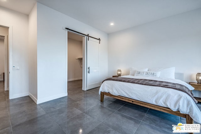 bedroom with dark tile patterned floors, a barn door, a spacious closet, and a closet