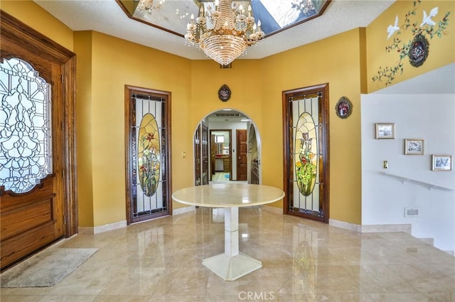 entryway featuring a skylight, a notable chandelier, and a textured ceiling