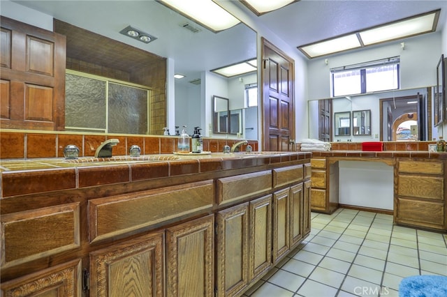 bathroom featuring a shower with shower door, sink, and tile patterned flooring