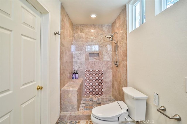 bathroom with toilet and a tile shower