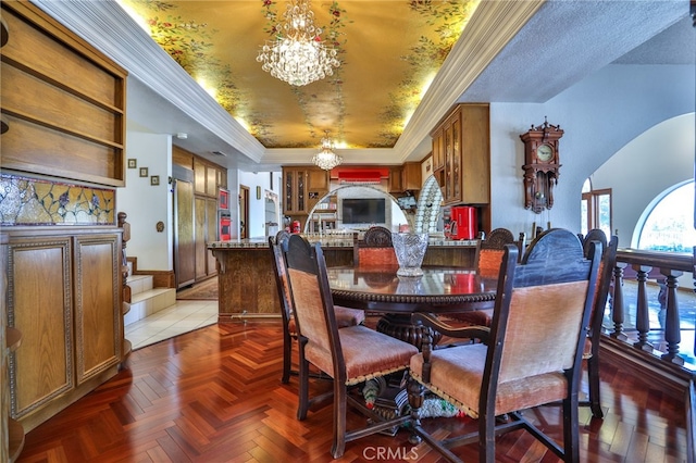 dining space featuring ornamental molding, dark parquet flooring, a raised ceiling, and a notable chandelier