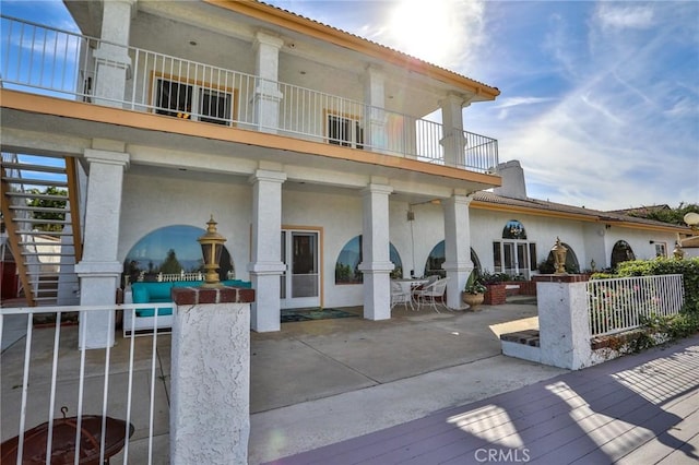 rear view of property featuring a balcony and a patio