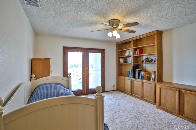 carpeted bedroom featuring ceiling fan, french doors, and a textured ceiling