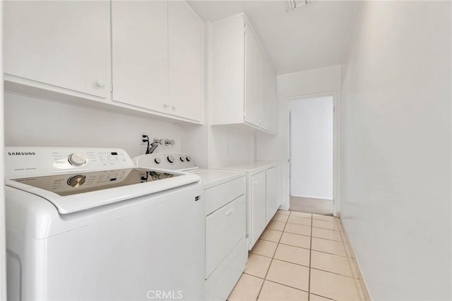 laundry area featuring cabinets, light tile patterned floors, and washing machine and clothes dryer