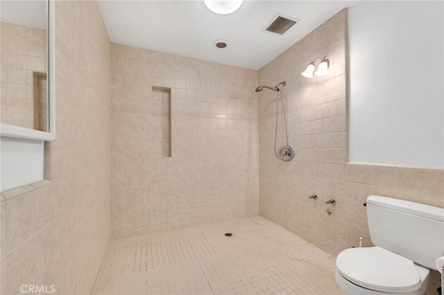 bathroom with tiled shower, tile patterned flooring, toilet, and tile walls