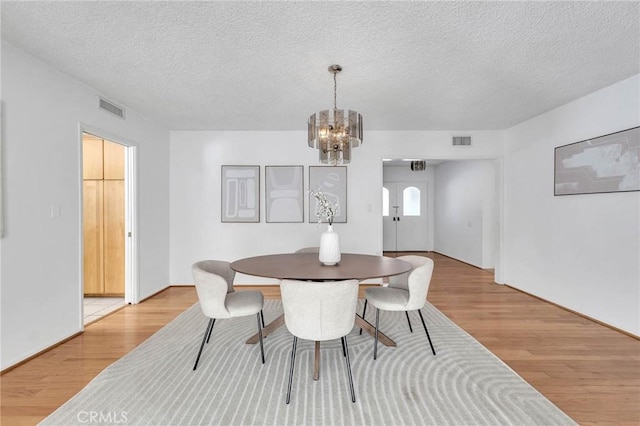 dining space featuring a chandelier, light hardwood / wood-style floors, and a textured ceiling