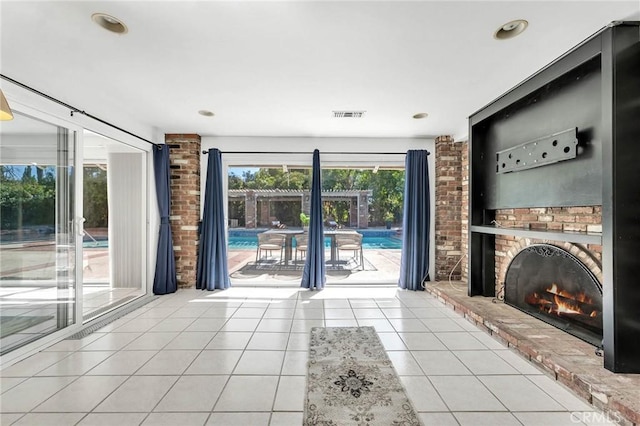 unfurnished living room featuring light tile patterned floors and a brick fireplace