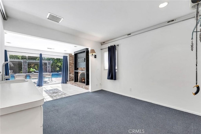 unfurnished living room with a fireplace, light colored carpet, and sink