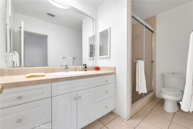 bathroom with tile patterned flooring, vanity, toilet, and walk in shower