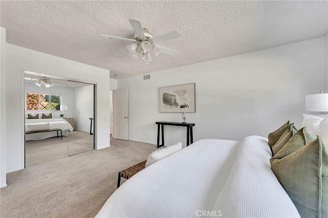 bedroom with a textured ceiling, light colored carpet, a closet, and ceiling fan