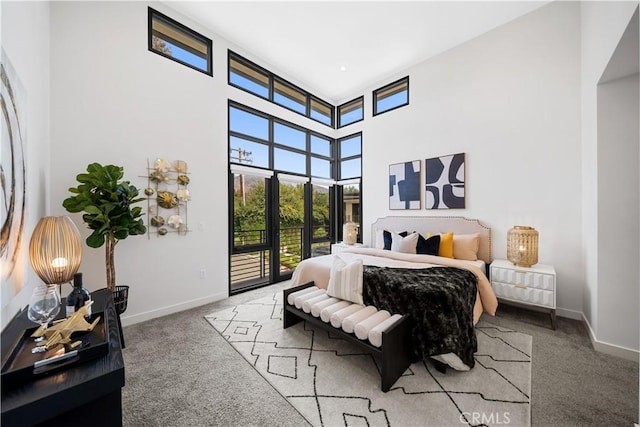 bedroom featuring access to outside, carpet floors, and a towering ceiling