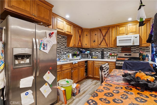 kitchen featuring sink, decorative backsplash, stainless steel appliances, and light hardwood / wood-style floors