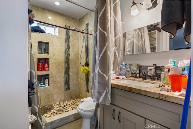 bathroom featuring vanity, toilet, and a tile shower