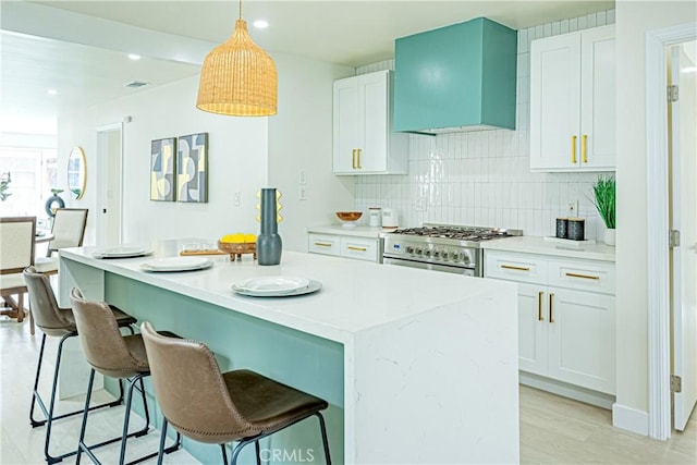 2942 S W View St, Los Angeles, CA 90016 - kitchen with high end stainless steel range oven, wall chimney range hood, a center island, decorative backsplash, and white cabinetry