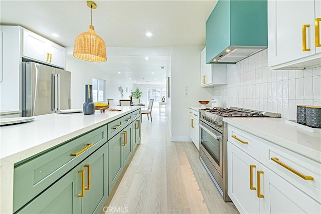 2942 S W View St, Los Angeles, CA 90016 - kitchen with stainless steel appliances, green cabinets, wall chimney range hood, light wood-style floors, and tasteful backsplash