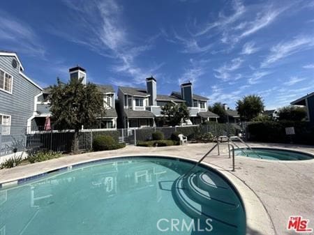 community pool featuring a residential view, a patio area, and fence