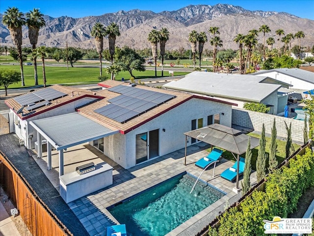 rear view of house with a fenced in pool, a mountain view, and a patio