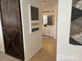 hallway with a barn door and light colored carpet