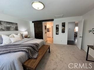 bedroom featuring connected bathroom, a barn door, and carpet