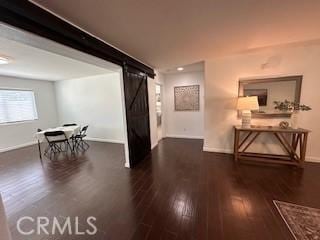 corridor with dark hardwood / wood-style flooring and a barn door