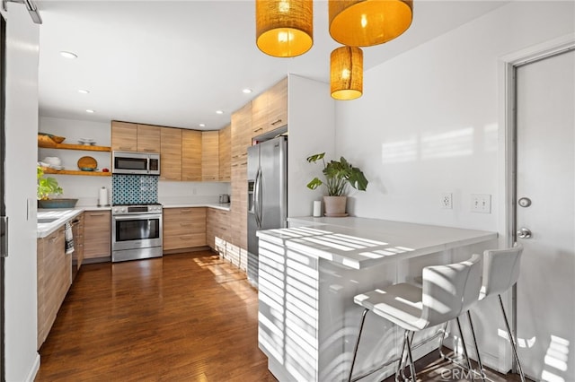 kitchen with pendant lighting, backsplash, stainless steel appliances, and dark wood-type flooring