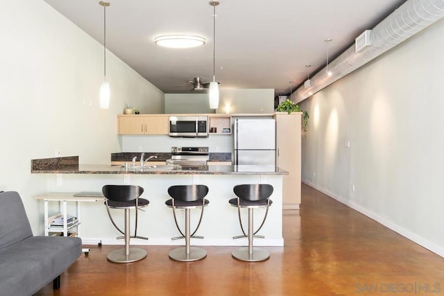 kitchen with appliances with stainless steel finishes, sink, kitchen peninsula, a kitchen breakfast bar, and pendant lighting