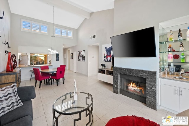 tiled living room featuring a healthy amount of sunlight, a stone fireplace, sink, and high vaulted ceiling