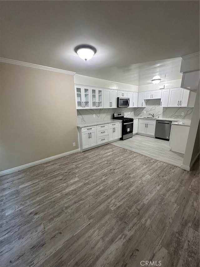 kitchen featuring hardwood / wood-style floors, white cabinetry, stainless steel appliances, and tasteful backsplash