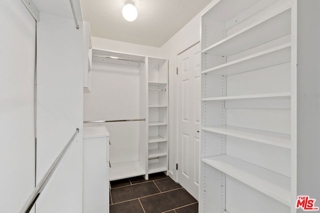 walk in closet with dark tile patterned floors