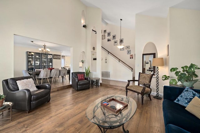 living room with a chandelier, a towering ceiling, and wood-type flooring