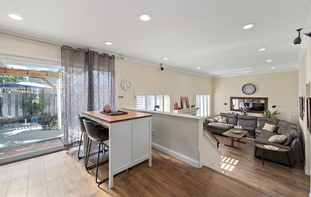 kitchen featuring a kitchen island, hardwood / wood-style floors, crown molding, white cabinetry, and butcher block counters