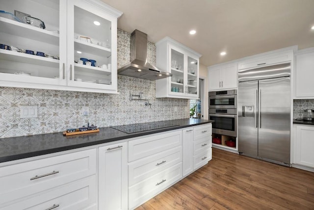 kitchen with white cabinetry, appliances with stainless steel finishes, tasteful backsplash, dark hardwood / wood-style flooring, and wall chimney range hood