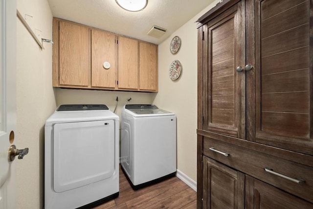 laundry room with dark wood-type flooring, cabinets, and washing machine and clothes dryer