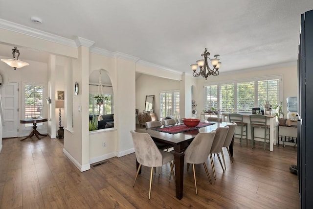 dining room with dark hardwood / wood-style floors, crown molding, and an inviting chandelier