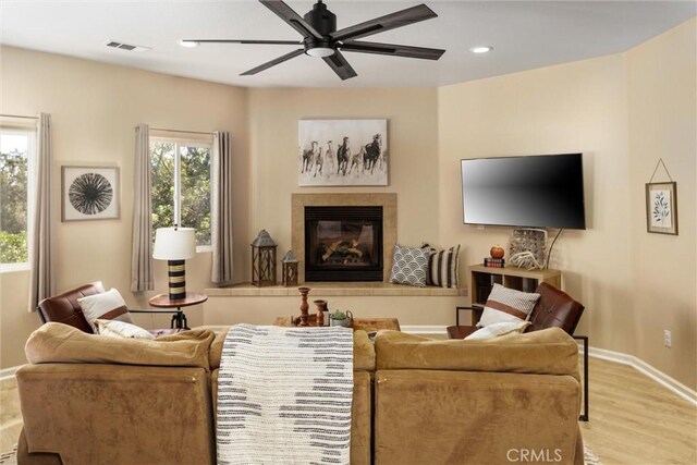 living room with light hardwood / wood-style floors, ceiling fan, and a fireplace